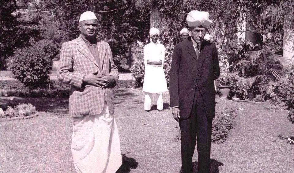 Sir M. Visvesvaraya seated with Madiah Gowda, both dressed in formal attire, posing together for a photograph.