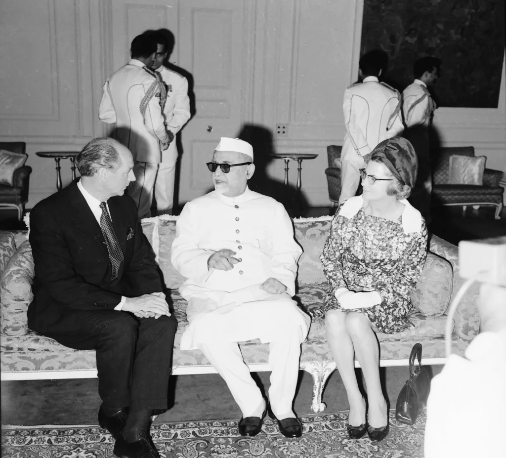 Dr. Zakir Husain, President of India, seated and engaged in conversation with an unidentified individual in a formal setting, likely during a state function in 1968.