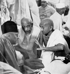 Mahatma Gandhi in discussion with Maulana Abul Kalam Azad and Sardar Vallabhbhai Patel, surrounded by others during a significant moment in India’s independence movement.
