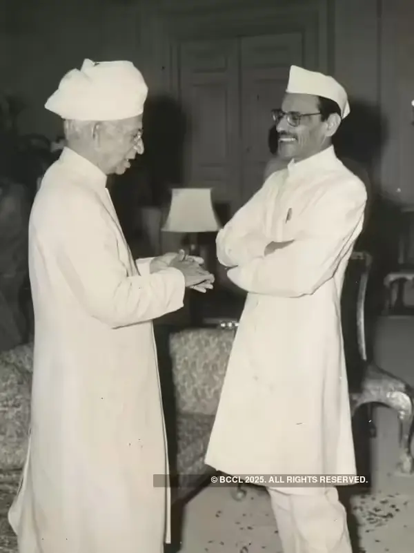Portrait of Gulzarilal Nanda in a white Gandhi cap and traditional attire, wearing round spectacles, against a plain background.