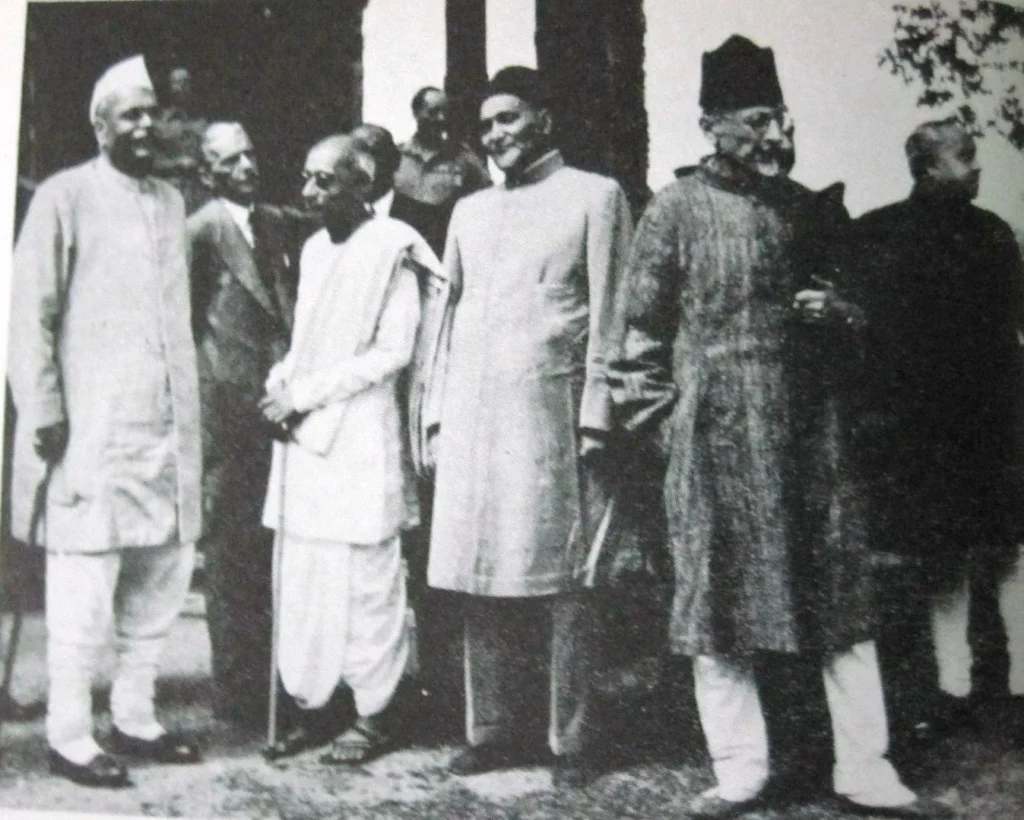 Indian leaders including Mahatma Gandhi, Sardar Vallabhbhai Patel, Maulana Abul Kalam Azad, and others, standing and conversing outside a building during the Indian independence movement.