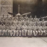 This vintage image shows a group of Indian Air Force personnel gathered in uniform inside an aircraft hangar, symbolizing camaraderie, teamwork, and the proud heritage of India’s military aviation history.