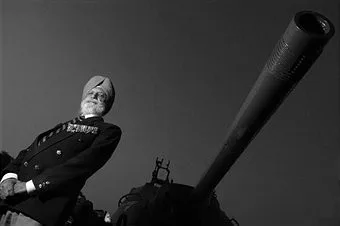 Indian Army officer in full dress standing beside a military artillery piece