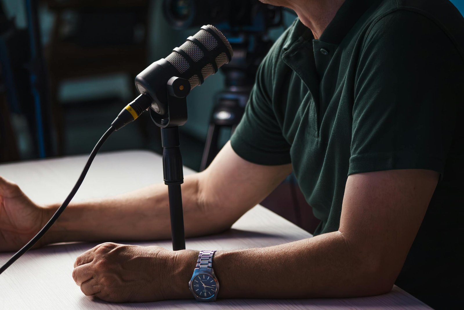 Close-up of a person recording a podcast in a studio, featuring a microphone and professional audio equipment.